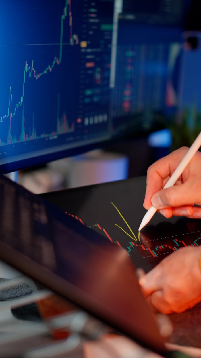 Mastering the First Impression: Your intriguing post title goes here Person using a stylus on a tablet for stock market analysis, with charts on a monitor.